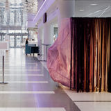 Kuvassa taideinstallaatio SOONI vaaleassa aulatilassa. Teoksen värikkäät tekstiilit liikkuvat teoksesta kantautuvan äänivirran mukana.