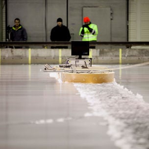 Three researchers using a device on the surface of the ice at Aalto ice tank