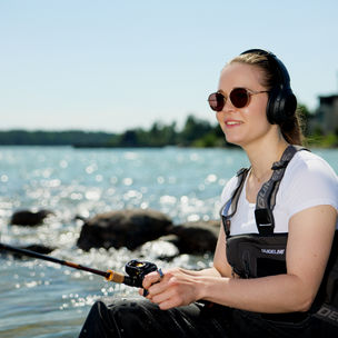 Woman fishing with headphones and listening an online course. Photo: Ari Toivonen