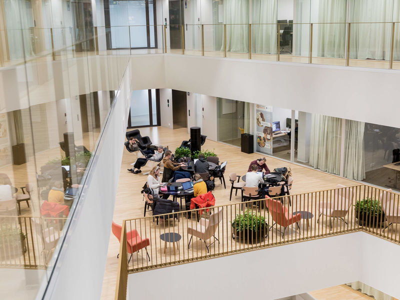 Groups of students sitting in work lounge inside the School of Business / Photo by Aalto University, Mikko Raskinen