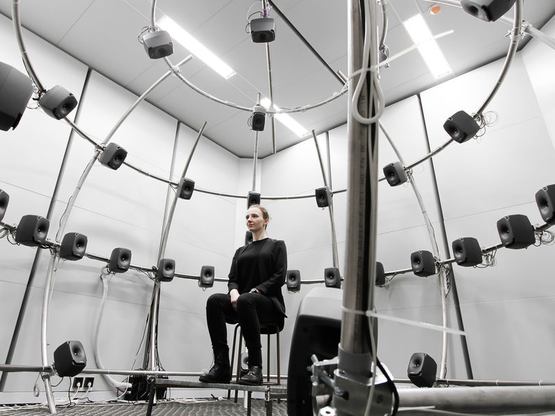 A person sitting at aalto acoustics lab's multichannel anechoic chamber photo benoit alary