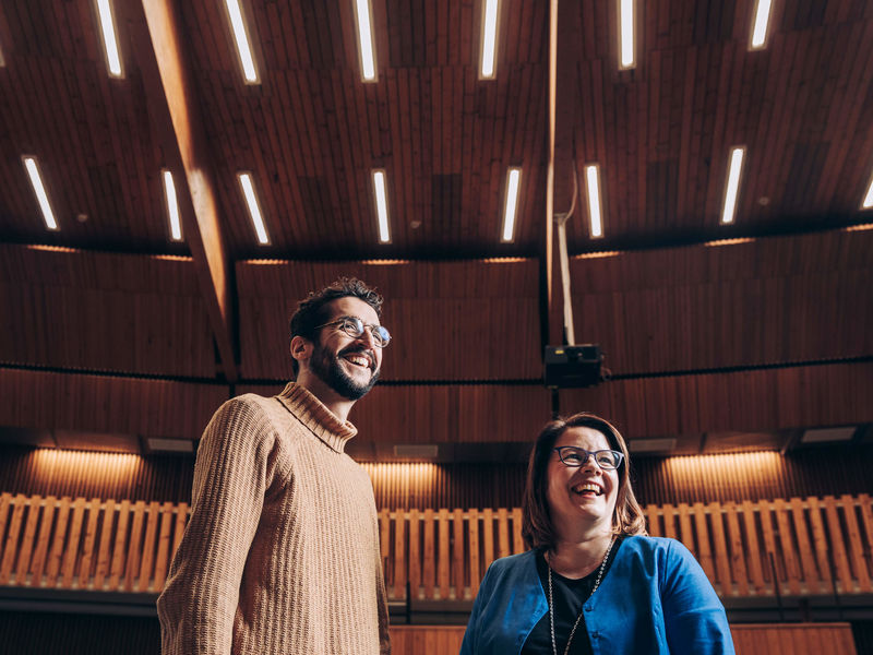 Two people standing and laughing in a lecture hall