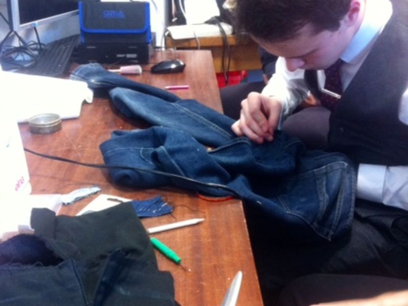 Mies korjaa farkkujaan käsin pöydän ääressä