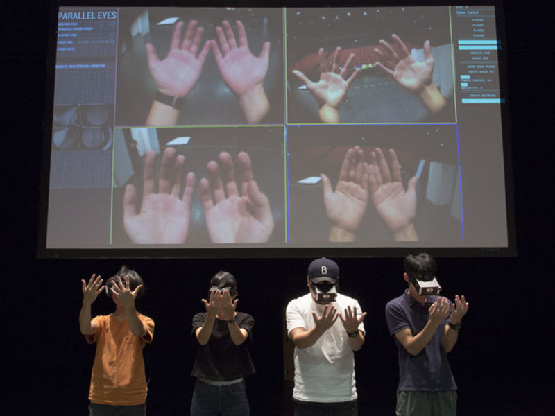 neljä ihmistä katsoo virtuaalilasit päässään omia käsiään, joiden kuva näkyy heidän takanaan isolla ruudulla