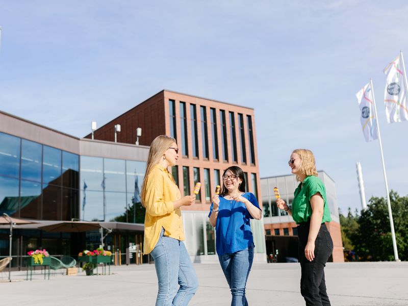 Three women talking and eating ice cream in front of the Väre building. 