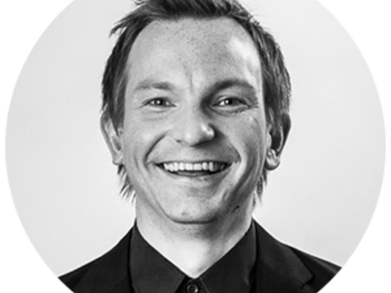 Black and white portrait of Peter Kenttä smiling towards the camera.