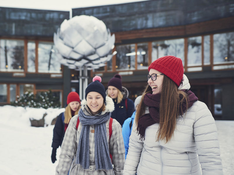 Laughing students in front of Dipoli in the winter, in warm clothing