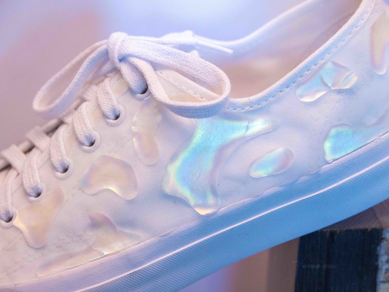 Close up of a white canvas sneaker with iridescent Shimmering Wood glitter patterns.