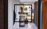 Space 21 logo taped on the glass door with the place itself visible through it.