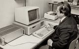 Mustavalkoisessa arkistokuvassa Teuvo Kohonen istuu vanhanaikaisen tietokoneen äärellä.