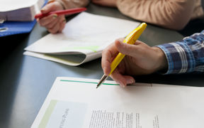 Two people with pens hovering over articles
