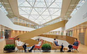 Neljä opiskelijaa Kauppakorkeakoulun uuden rakennuksen aulassa juttelemassa ja opiskelemassa.