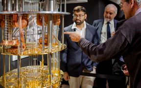 Three people look at a quantum computer