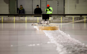 Three researchers using a device on the surface of the ice at Aalto ice tank