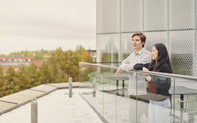 Kaksi opiskelijaa seisomassa Kauppakorkeakoulun kolmannen kerroksen terassilla