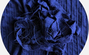 Blue fabric scraps and yarn against blue background.