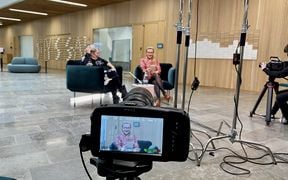 Filming the Back to Work Sessions series. This photo is capturing speakers Hilkka Olkinuora and Hertta Vuorenmaa through a camera lens while they are sitting and discussing next to each other in green chairs.