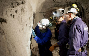 People wearing helmets and examining a tunnel wall