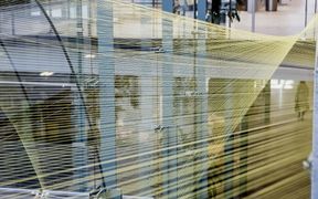 Photo of yellow strings wrung infront of a glass wall