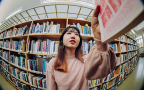 A student taking a book from a shelf in Aalto University's library.