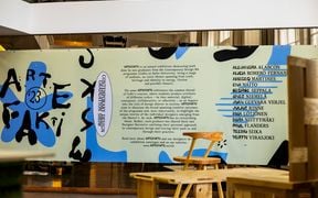 A large printed ARTEFAKTI presentational panel with artists' names and exhibition text