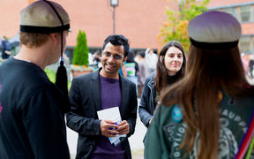 A man and a woman talking to two students wearing teekkari hats