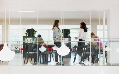People talking and working in the café in Harald Herlin Learning Center, white lamps hanging in front.