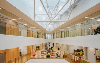 Architectural picture of the inside of the School of Business. Many people sitting on different coloured chairs.