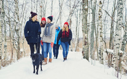 Aalto University students walking with a dog in the wintery Otaniemi.