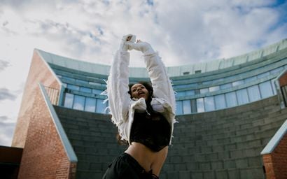 A woman dancing in front of a big building