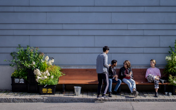 Two students talking to two festival visitors who are sitting on a bench.