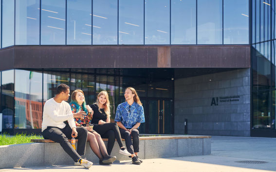 Four students sitting outside the School of Business