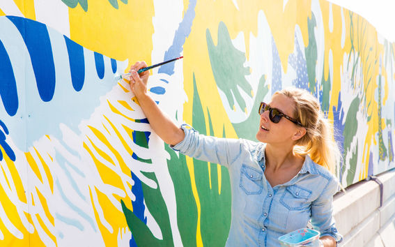 A girl with sunglasses paints a wall at Flow festival site