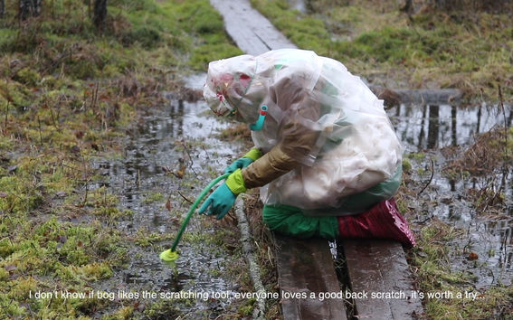 A person dressed in a protective suit is trying to scratch a bog. (Short art movie.)