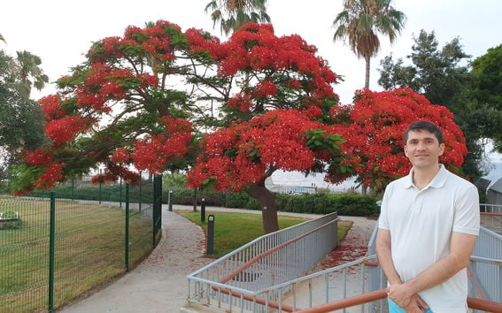 Associate Professor Ali Tehrani standing in front of blooming trees.