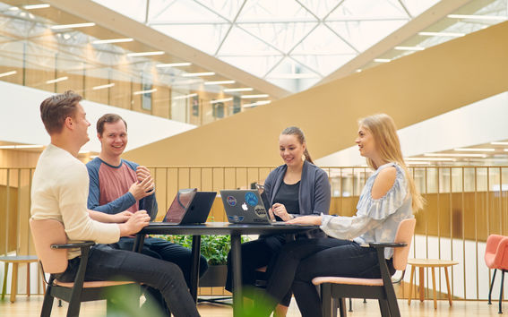 Four happy students in Aalto BIZ. Photo: Unto Rautio / Aalto University