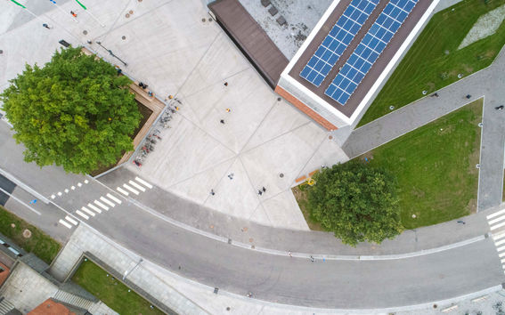 Aerial shot of the Korkeakoulunaukio square. There are solar panels on the Väre roof and trees on the square.