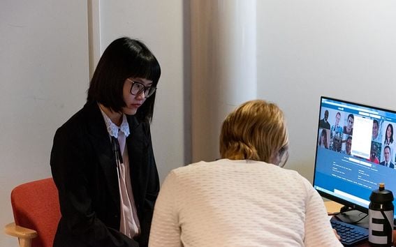 Two women sitting by a computer looking at a video chat
