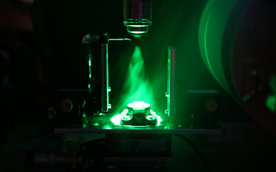 A green laser light shining on a sample stage between two magnets