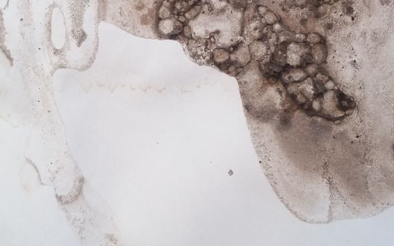 Kuvassa on likaisia ruskeanharmaita tahroja ja sulamisjälkiä valkoisella pohjalla.