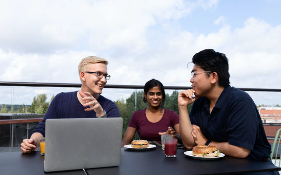 Students discussing around a laptop on an outside terrace during a summer course at Aalto University Summer School.