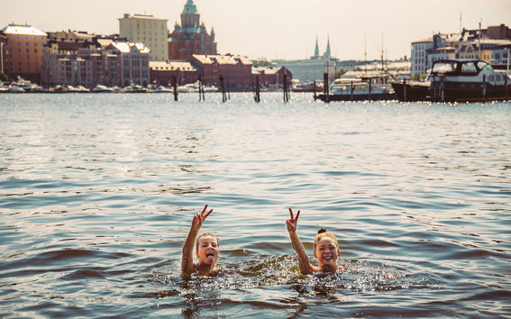 Two women swimming in Helsinki city outside the Uspenski Cathedral.