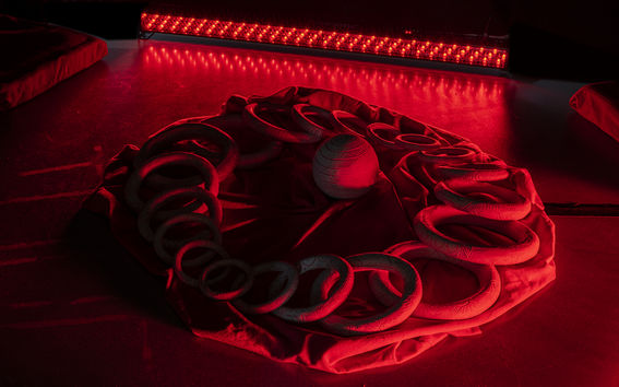 photo of installation made of ceramic circles and a ball in red light