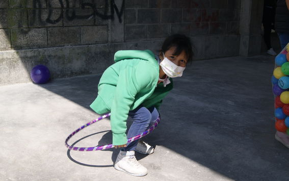Care spaces- A play street in Mexico city, with a young girl playing with a hula hoop