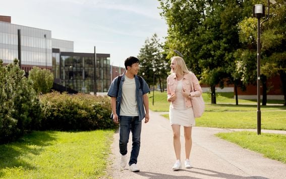 Two students walking on campus, chattering and laughing together.