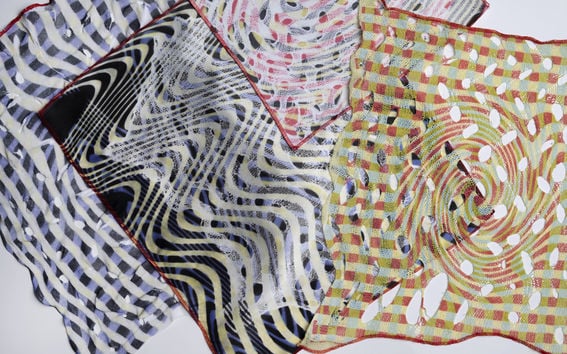 Erilaisia värikkäitä digitaalisesti tulostettuja tekstiilikuoseja lomittain vaalealla tasolla 