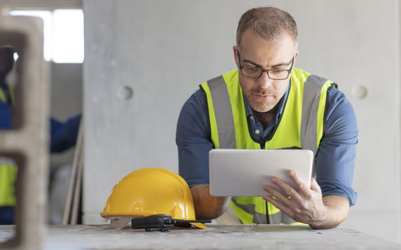 A man uses a tablet computer at a construction site.
