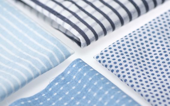 Four pieces of cloth in striped, plaid and polka dot patterns, dyed different shades of blue