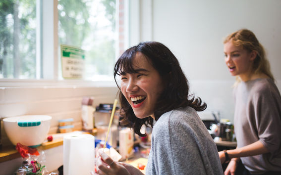Two Aalto University students laughing while experimenting or cooking on campus.
