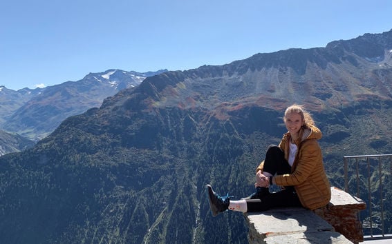 BScBA alumna Julia Romanyuk sitting in front of mountain landscape